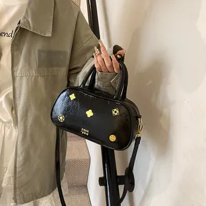 Glossy black Boston handbag with gold metal hardware and detachable shoulder strap