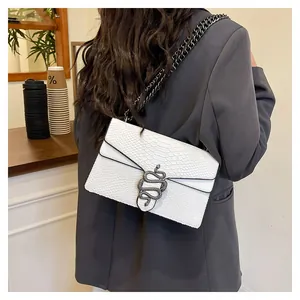 Detailansicht einer weißen Tasche mit Schlangenhautmuster und metallener Schlangenschnalle