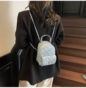 Back view of a light blue quilted mini backpack with silver studs and chain straps