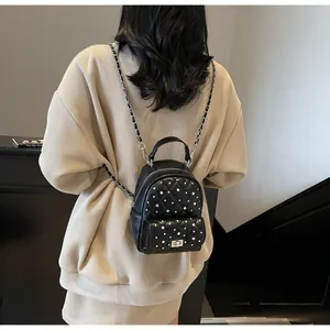 Detail of black quilted backpack with pearl studs, metal twist lock and chain strap
