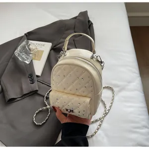 Detail of cream quilted mini backpack with sparkling rhinestones and silver chain strap