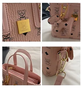 Detail view of pink leather bag featuring cartoon bear print and gold metal logo plaque