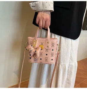 Detailed view of pink printed handbag featuring teddy bear patterns and dog charm accessory