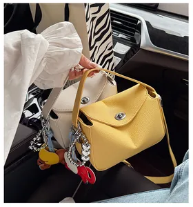 Détail de sacs demi-lune en cuir grainé avec breloques cœur en métal et pendentif éléphant