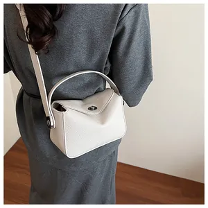 Gros plan sur la texture du cuir crème et le fermoir métallique argenté d'un sac à main