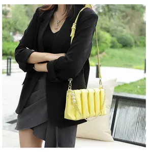 Detail of yellow pleated shoulder bag featuring pearl decor and gold metal chain