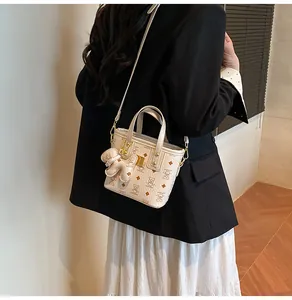 Close-up of stylish bear print bucket bag with golden hardware and teddy charm