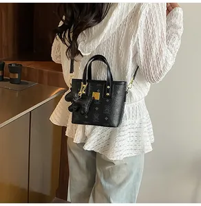 Detail of black bucket bag with bear print, gold metal plaque, and bear charm accessory
