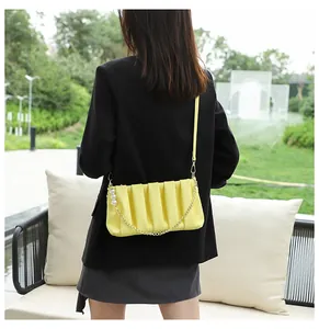 Detailed view of yellow pleated PU leather shoulder bag with gold chain and pearl accent