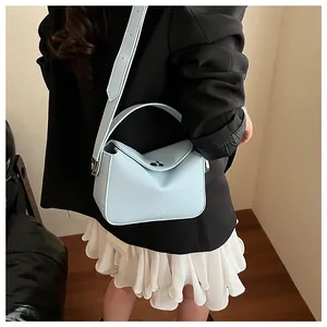 Vue détaillée du sac à bandoulière en cuir bleu clair à motif litchi avec ferrures