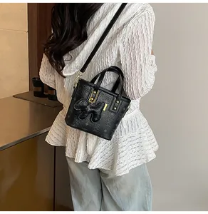 Detail of a black patterned bucket bag with a cute rabbit plush charm on a model
