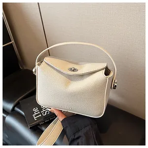 Gros plan sur la texture cuir grainé crème et le fermoir métallique du sac à main