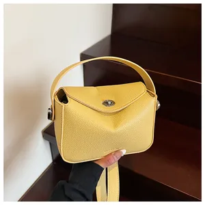 Gros plan d'un sac à main jaune en cuir litchi avec fermoir tournant métallique argenté
