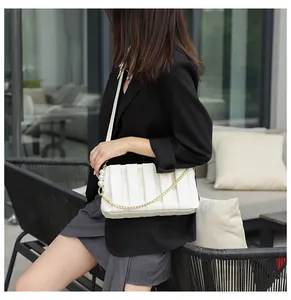 Detail of white pleated shoulder bag with golden chain and elegant pearl decorations