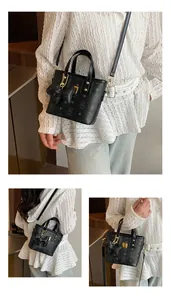 Detail view of black printed bucket bag with bear charm and adjustable shoulder strap