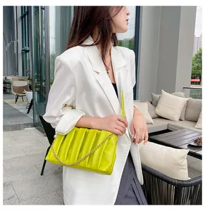 Lime green pleated bag with pearl chain strap styled with a white blazer and dress