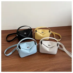 Détail de petits sacs en cuir en quatre couleurs avec fermoir rotatif sur sol en bois
