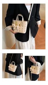 Detail of cream tote with bear prints, gold hardware, and a matching bear charm