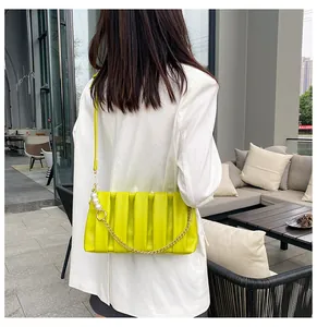 Detail of neon green pleated baguette bag with pearl chain and gold hardware accents