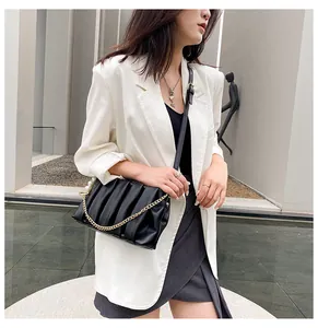 Detail of black pleated crossbody bag with fine gold chain and pearl charm detail