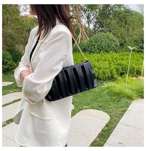 Detail showing elegant pleated black leather texture and delicate gold chain strap