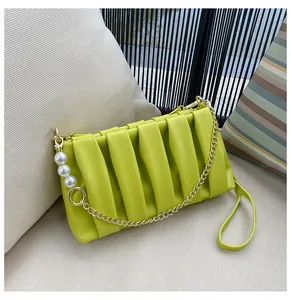 Detail of neon green pleated handbag featuring gold metal chain and pearl decorations