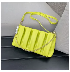 Detail of neon green pleated shoulder bag with pearl accents and gold metal chain