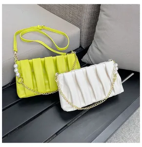 Detailed view of pleated leather handbag with large pearl accents and gold chain strap
