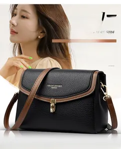 Close-up of black litchi grain leather bag with brown trim and gold hardware clasp