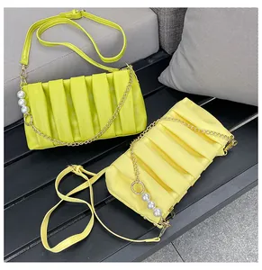 Detail of pleated crossbody bags with pearl chain strap and adjustable leather belts