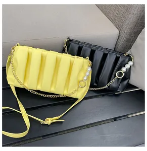 Detail of yellow and black pleated square bags with pearl and gold metal chain straps