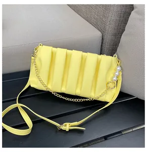 Detail of yellow pleated shoulder bag featuring elegant pearl gold chain and strap