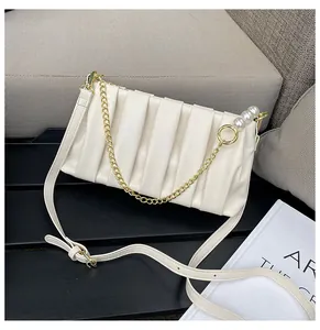 Detail of cream pleated crossbody bag with pearl charms and gold chain hardware