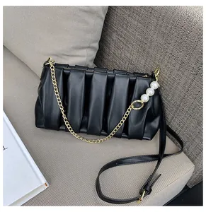 Detail of pleated black crossbody bag with gold chain and three pearl accents