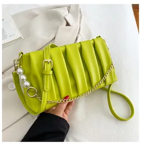 Detail view of avocado green pleated bag with pearl charms and gold metal chain strap