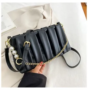 Detail of black pleated PU handbag with gold chain strap and large faux pearl charms