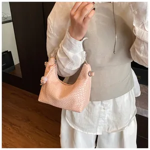 Détail du sac sous le bras tissé rose clair avec perles translucides sur la poignée