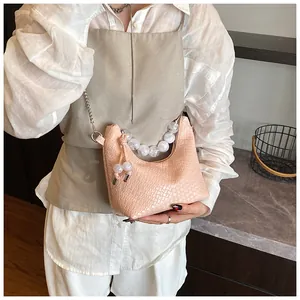 Détail du sac lune rose texture croco avec poignée en perles mates et chaîne en métal