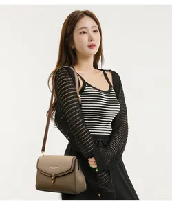 Close-up of two-tone leather crossbody bag with golden metal twist lock on a model