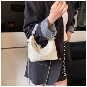 Détail du sac sous l'aisselle blanc tissé avec poignée en perles et chaîne argentée
