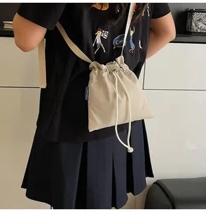 Détail de la fermeture à cordon et de l'étiquette tissée bleue sur le sac seau beige