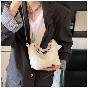 Détail du sac crème avec texture en similicuir et poignée en perles élégantes