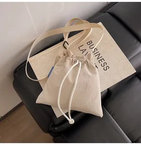 Détail du sac bandoulière beige à cordon avec étiquette bleue NINGNING sur le côté