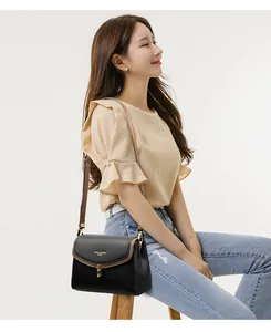 Detail view of the black and brown leather crossbody bag with a golden metal twist lock