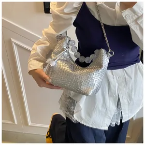 Détail d'un sac sous le bras tissé argenté avec poignée en perles sur le mannequin
