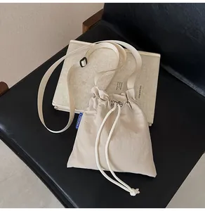 Détail du sac seau en nylon imperméable avec plis posé sur une chaise en cuir noir