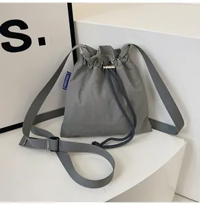 Détail du sac seau en nylon gris imperméable montrant le cordon de serrage et l'étiquette