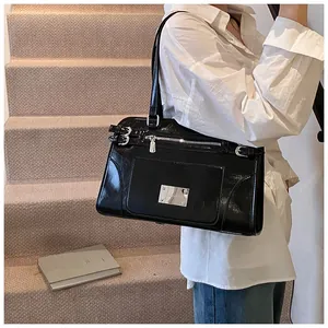 Detail of glossy black laptop bag with silver hardware and metallic logo plate