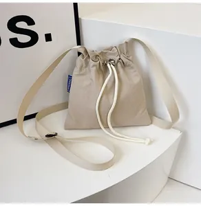 Détail du sac seau en nylon imperméable beige clair avec cordon et étiquette tissée bleue