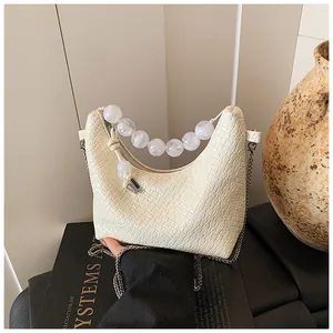 Détail du sac crème texture crocodile avec grandes perles et bandoulière chaîne